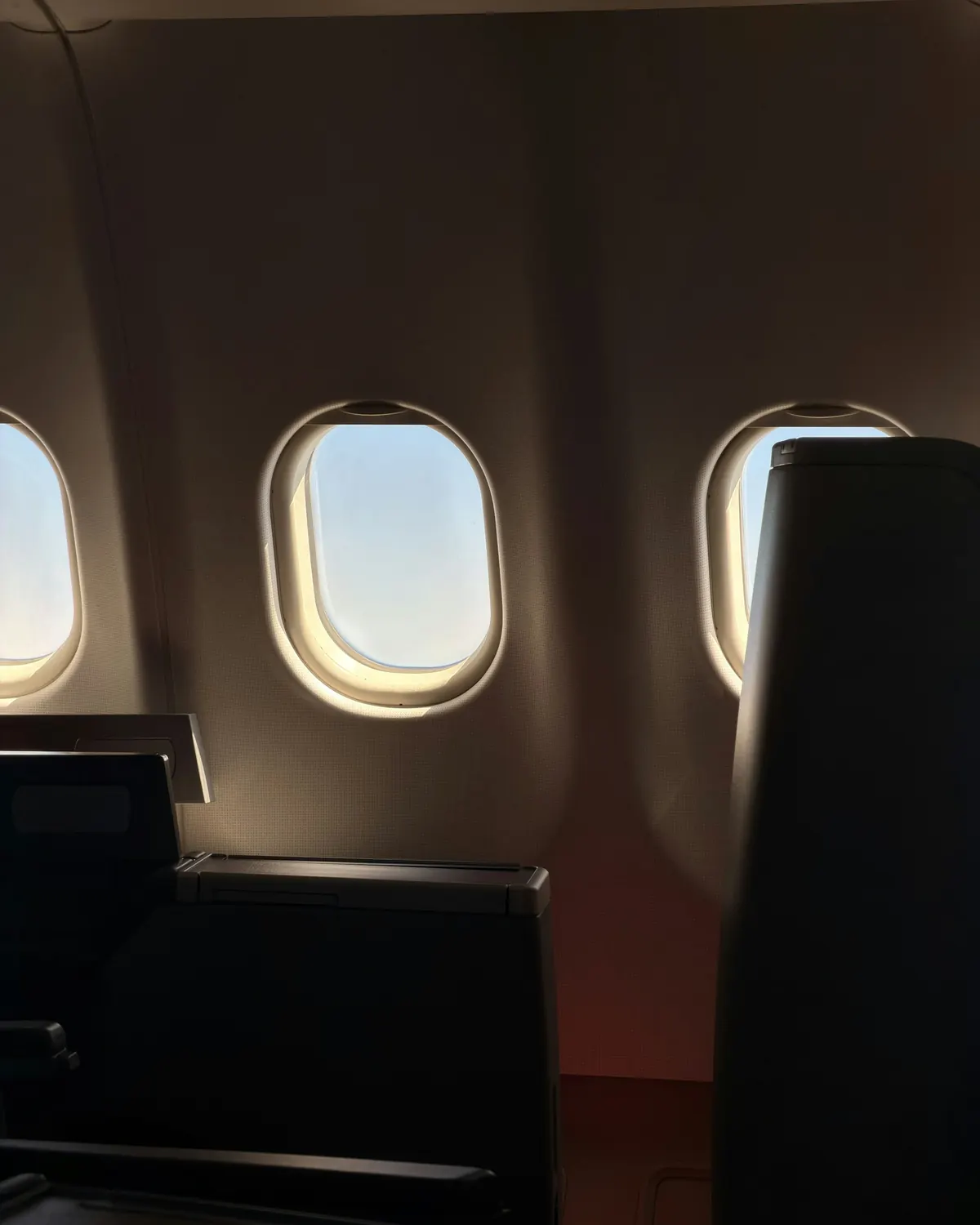 A darkened private jet cabin with light through the windows