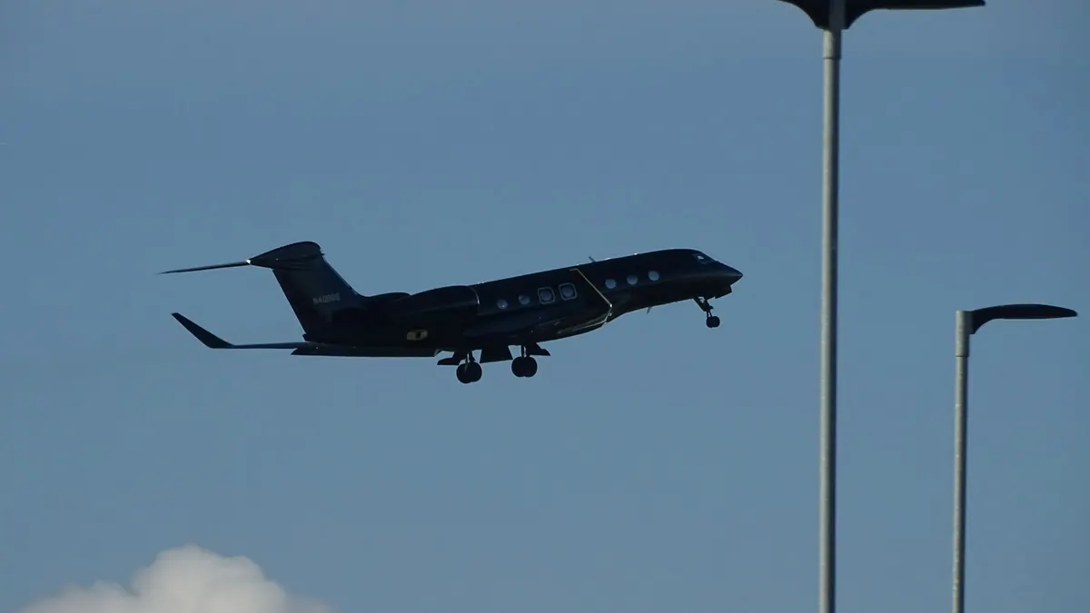 A business jet climbing past airport light poles